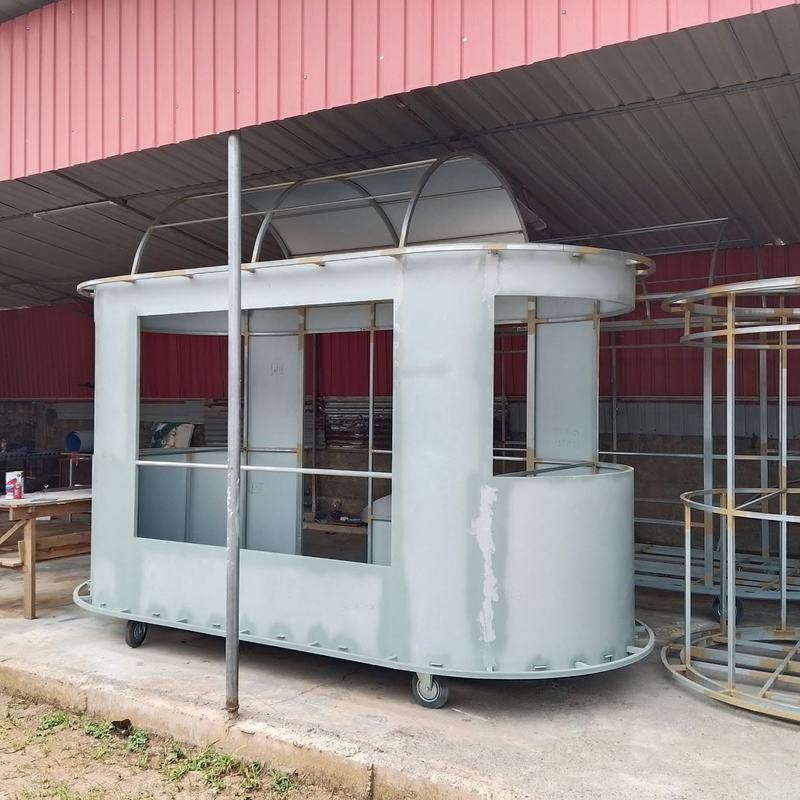 A primed kiosk shell on castors with its curved roof ribs in place, beside another frame being built