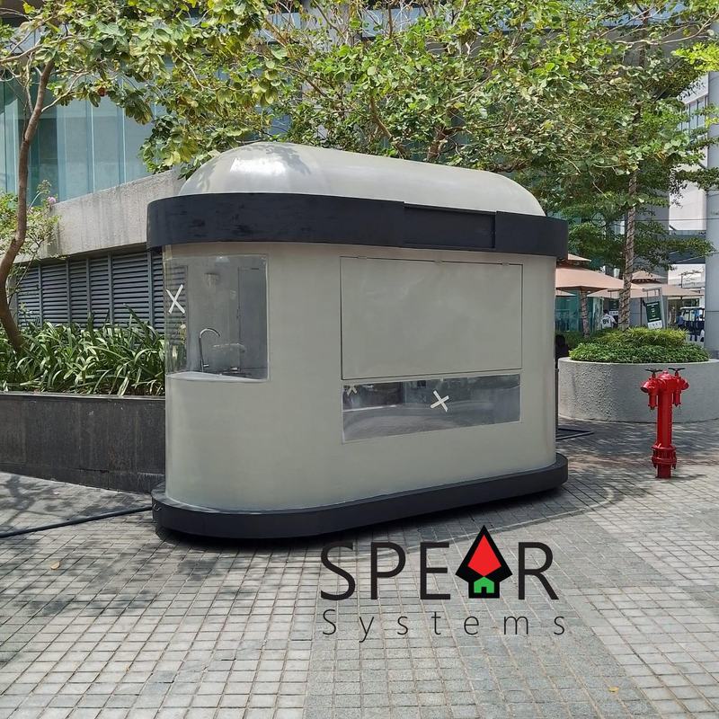 A cream and charcoal kiosk with a domed roof and rounded corners, closed up, standing on the mall walkway