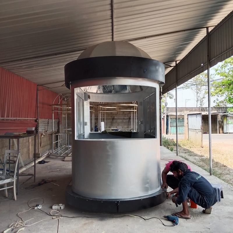 A fabricator fixing the base trim on a round kiosk with a domed roof in the workshop